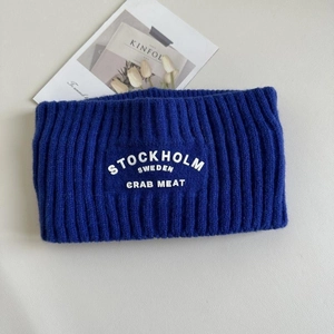 Detail eines dunkelblauen Strickstirnbands mit weißer Stockholm Schweden Stickerei