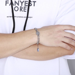 Detail of silver stainless steel Cuban link chain with smiley face charm on wrist