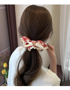Close-up of a red and white checkered scrunchie with lace trim and a brown bear bow detail