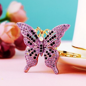 Macro detail of a purple butterfly keychain with sparkling rhinestones and gold metal frame