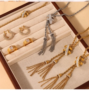 Detail shot of gold and silver tassel necklaces with rhinestone hoop earrings and wide rings