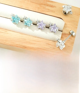Macro detail of star-shaped zircon stud earrings with flat back barbell screw design