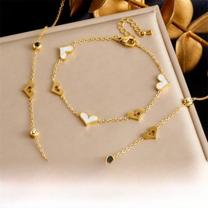 Detail of gold heart necklace and bracelet set with white mother of pearl inlay