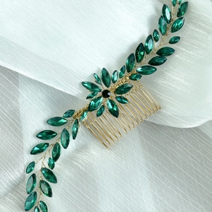 Macro detail of bridal hair comb with green marquise crystals and golden branch design