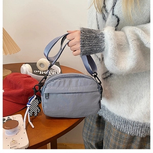 Détail du sac bandoulière en nylon imperméable gris-bleu avec charm en damier