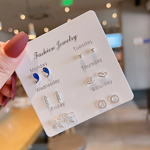 Detailed view of silver weekday earring set featuring heart, flower, and bow designs