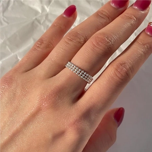 Macro detail of a 925 sterling silver beaded minimalist ring on finger with white background