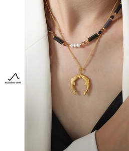 Detail of layered stainless steel necklace with natural stones and gold fish pendant