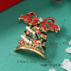 Detailed view of Christmas bell brooch with red and green crystals on textured green background