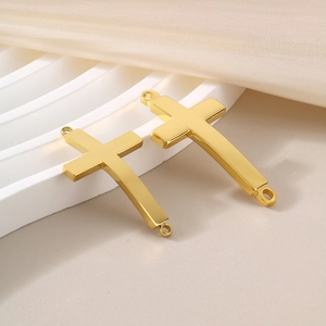 Macro view of gold curved cross pendant connector with dual rings on velvet surface