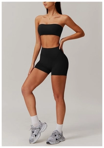 Detail view of black high-waisted fitness shorts and sports top on a model in studio