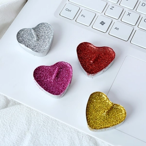 Close-up of four heart-shaped glitter tea light candles in gold, red, and silver