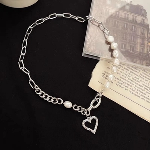 Elegant pearl heart pendant necklace with mixed silver metal chain on dark background