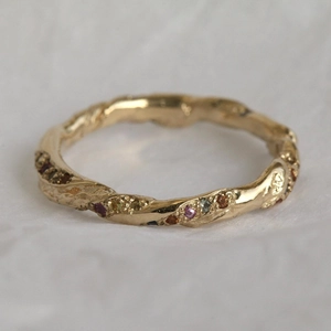 Irregular spiral 18K gold plated ring with colorful zircons on a textured surface