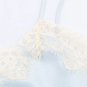 Close-up of light blue fabric with delicate cream lace trim detailing on the top