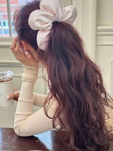 Detail of a large champagne silk scrunchie with soft satin luster worn on a ponytail