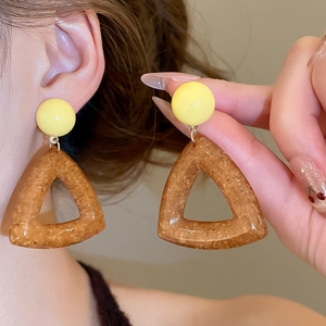 Detail of geometric resin earrings with yellow circle and brown triangle glitter charms