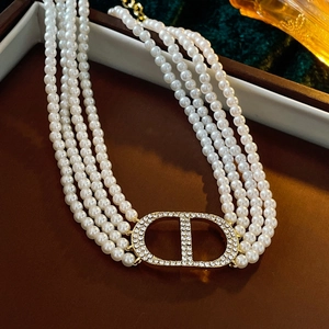 Close-up of four-layer pearl necklace with a sparkling rhinestone CD letter buckle