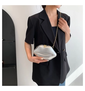 Detail der metallisch silbernen Lippen-Tasche mit goldener Kette am Model getragen