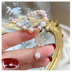 Detail of freshwater pearl bracelet with zircon flower pendant held by hand