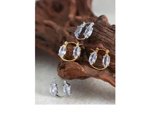 Dettaglio di orecchini con zirconi a marquise in oro e argento su base in legno