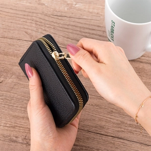 Close-up of black lychee leather accordion card wallet with golden metal zipper detail
