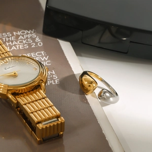 Detail of luxury two-tone asymmetric open ring paired with a golden fashion watch