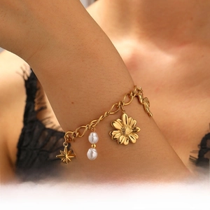 Détail d'un bracelet doré avec breloques tournesol, étoile et perles sur de gros maillons