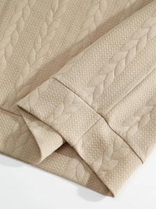 Detailed close-up of light beige jacquard knit fabric showing waffle texture and patterns