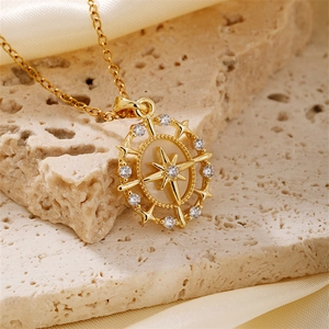Luxurious gold starburst compass necklace with zircon accents on champagne silk background