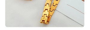 Detail eines hochglanzpolierten goldenen Titanstahlarmbands im klassischen H-Glied-Design