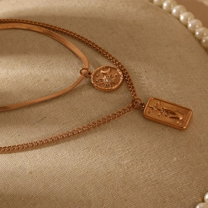 Detail of rose gold double-layered necklace with sun circle and star rectangle pendants