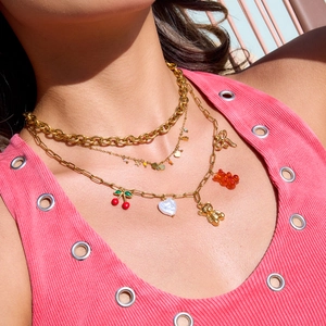 Detail of layered gold necklace with cherry, bear and heart pendants on model