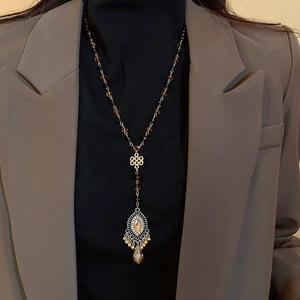 Detail of vintage beaded necklace with Chinese knot metalwork and hollow pendant on a model