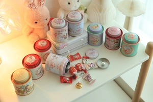 Macro view of mini bunny tin canisters with double lids and cute hand-painted illustrations