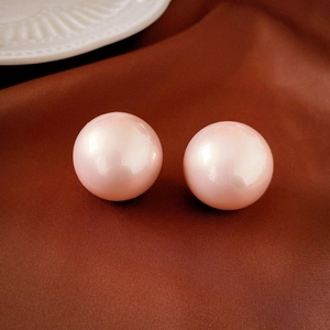 Detail shot of round pink faux pearl stud earrings with smooth glossy finish and silver pins