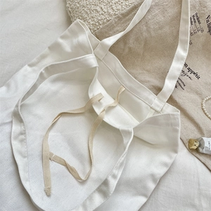 Detail view of minimalist cream canvas tote bag showing strap and durable texture.