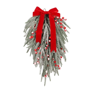 Christmas teardrop wreath with large red velvet bow and snowy pine needles on white background