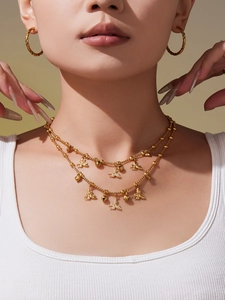 Gedetailleerd beeld van gelaagde gouden ketting met bij- en kralenhangers bij een model