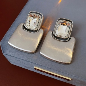 Macro shot of silver brushed metal rectangular earrings with large square rhinestones