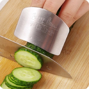 Stainless steel finger guard for slicing vegetables on a wooden cutting board