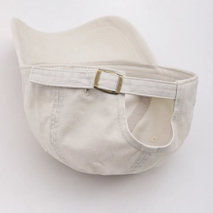 Détail de la casquette de baseball beige en coton avec boucle métallique réglable au dos