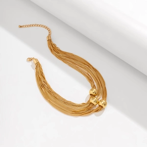 Detail of gold multi-layer chain necklace featuring three sphere pendants and lobster clasp