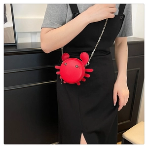Red crab-shaped crossbody bag with gold chain strap shown on a model's outfit
