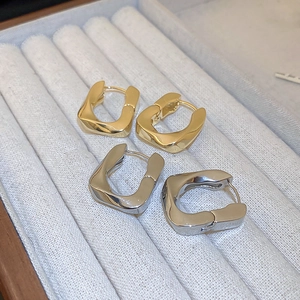 Gros plan de boucles d'oreilles dorées et argentées torsadées en U sur velours