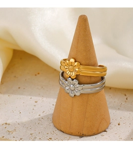 Detail of adjustable gold and silver floral rings on a wooden stand with silk background