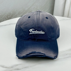 Distressed dark blue baseball cap with Fantastic embroidery on marble surface