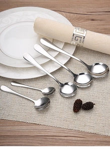 Set of six polished stainless steel spoons in two sizes on an elegant dining table set