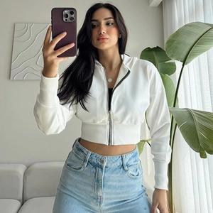Detail of a white zip-up hooded knit cardigan paired with light blue high-waist denim jeans