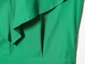 Detailed close-up of emerald green ruffled romper fabric showing fine stitching and texture